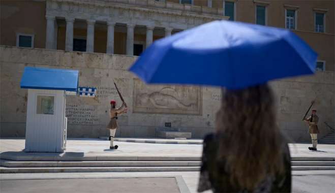Με ομπρέλες και καπέλα προστατεύονται οι πολίτες από τη ζέστη και τον ήλιο  AP Photo/Petros Giannakouris